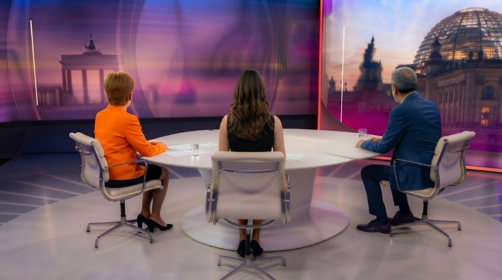 Studio-Moment im Fernsehstudio — drei Personen am Tisch, LED-Hintergrund Berlin